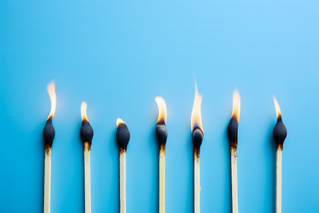 Burning match on a blue background. Conceptual image of fire.の素材