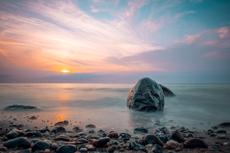 Beautiful seascape with a stone in the sea at sunsetの写真素材