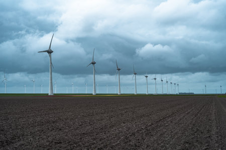 Wind turbines in a field in the Netherlands under a cloudy sky.の写真素材