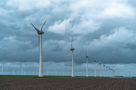 Wind turbines in a field under a stormy sky in the Netherlandsの写真素材