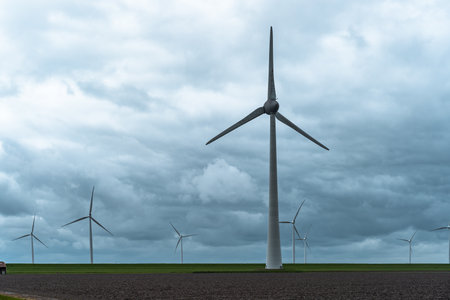 Wind turbines in a field in the Netherlands with a cloudy sky.の写真素材