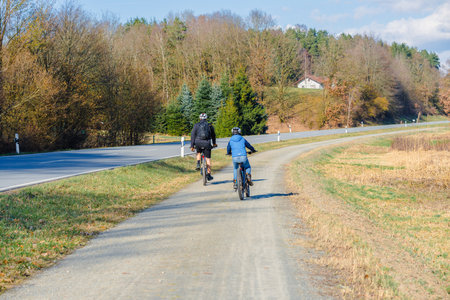 Cyclists on a country road in the autumnal park.の写真素材