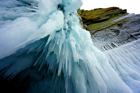 Blue ice waterfall sprinkled with water on green rocks
