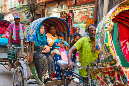 Dhaka, Bangladesh-November 14, 2019: A brightly colored rickshaw. The main means of transportation on the local streets. Unknown women and children sitting on rickshaws. Rickshaws, drivers and passengers enrich the colorful streets of Dhaka.のeditorial素材