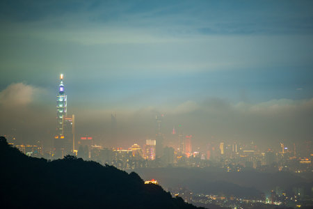 City lights and changing clouds: a spectacle viewed from the top of a mountain. View of the urban landscape from Dajianshan Mountain, New Taipei City, Taiwan.の写真素材