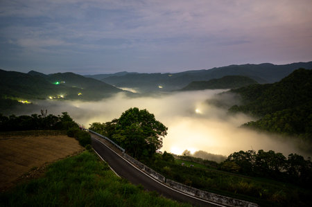 The sun penetrates the clouds and spills into the valley. Early morning view of tea gardens, sea of ââââclouds and sunrise, Nanshan Temple.の写真素材