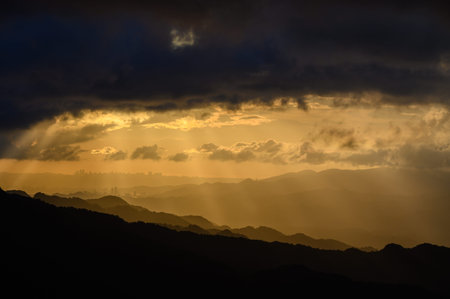 The sun's rays broke through the clouds and shone on the mountaintops and towns. Silhouettes of...