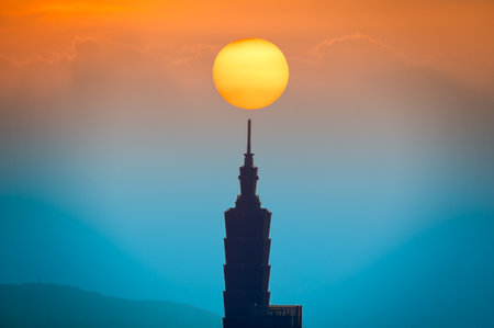 A combined view of the moving sun and city tower landmarks at sunset. Urban Warmth: Afternoon Sunlight and the Orange City Silhouette in Fall.の写真素材