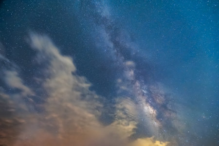 Night starry sky. The Milky Way is about to be covered by white clouds. View of the mountains...