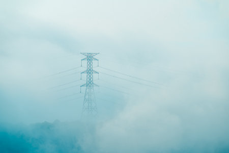 A high voltage tower and a sea of raging, tumbling clouds on a summer morning. View of the mountains surrounding Emerald Reservoir. Xindian District, Taiwan.の写真素材