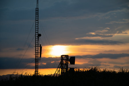 A striking sunset with vivid orange and purple hues over a radar station. Silhouetted communication...