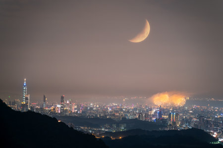 A breathtaking night view of Taipei City skyline with fireworks and a crescent moon on Qixi Festival. The romantic atmosphere is enhanced by the celestial bodies and the vibrant city lights, Taiwan.の写真素材