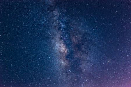 A breathtaking view of the Milky Way stretching across the night sky above a calm sea. The starry band of our galaxy is visible in all its glory.の写真素材