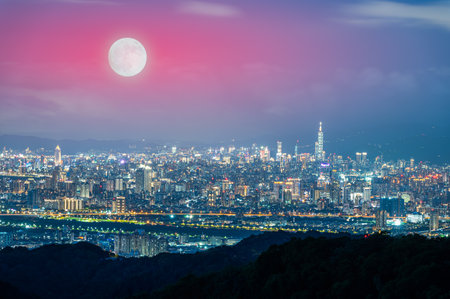 A golden autumn moon hangs over the Taipei skyline, casting a warm glow on the city. The scene captures the tranquility of an autumn evening. Taipei City, Taiwan.の写真素材