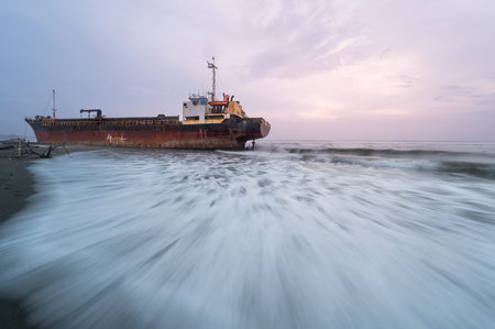 A solitary abandoned ship rests on the shore of Xigushui Beach, its weathered hull and rust-stained...