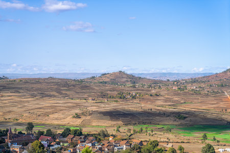 Vast farmland with green and brown patches under a clear blue sky. Rolling hills in the background. Isalo National Park, Madagascar.の写真素材