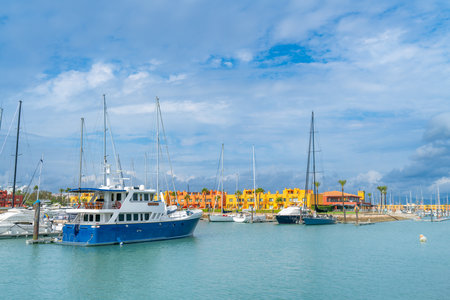 A vibrant marina with yachts docked, featuring a striking blue yacht in the foreground. Colorful buildings and palm trees in the background, Marina De Portimao, Portugal.の写真素材