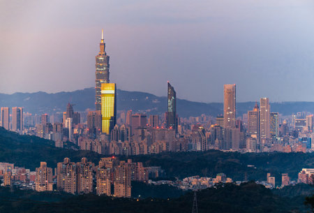 A breathtaking view of Taipei cityscape from Dajian Mountain, in the early spring morning. The golden sunlight bathes the buildings. The sky is a canvas of pink and orange hues. Xizhi, Taiwan.の写真素材