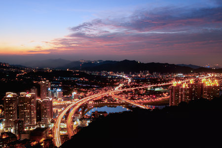 A stunning cityscape at dusk featuring brightly lit highways and high-rise buildings. Shizaitou...