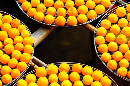 Large trays of orange persimmons drying in the sun. This is a step in the process of making dried persimmons. Xinpu Township, Hsinchu County, Taiwan.の写真素材