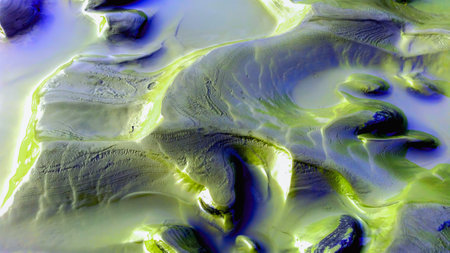 Clear green river water and layered clay riverbank in morning. Light and shadow on earth tone mud,...