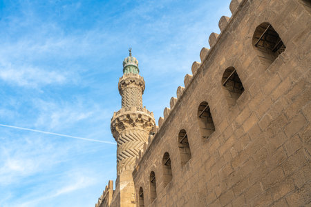 A detailed view of the minaret and stone walls of the Mohamed Ali Mosque, showcasing its Ottoman architectural style. A symbol of 19th-century Egyptian modernization.の写真素材