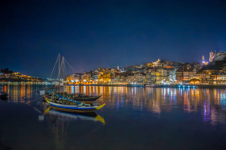 Porto, Portugal: Night view of Douro River with illuminated city skyline and traditional Rabelo...