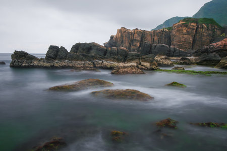A serene coastal rock formation at Jiufen, Taiwan, showcasing unique textures and patterns against a...