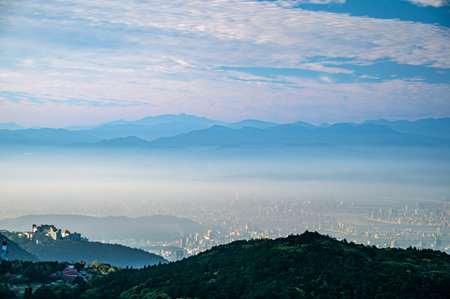As dawn breaks over Datun Mountain, soft clouds cradle Taipei's skyline in a dreamlike embrace,...