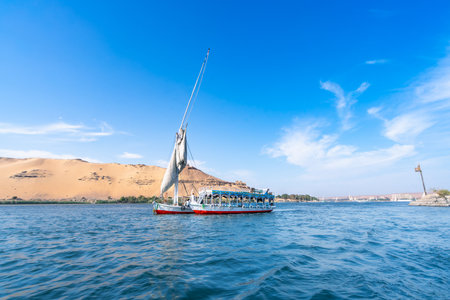 A felucca sailboat carrying tourists cruises along the Nile River near Aswan High Dam, Egypt, on a...