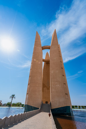Tourists visit a monument surrounded by palm trees and gardens. A vibrant spring scene.の写真素材