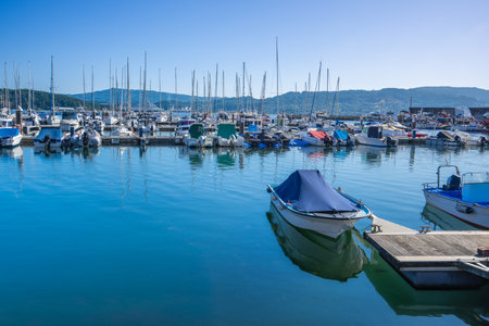 A vibrant marina scene in Baiona Bay, Spain, with numerous boats and yachts moored under a clear blue sky, ideal for summer travel and leisure.の写真素材