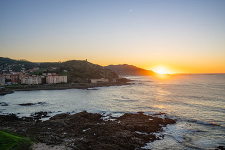 A breathtaking view of Baiona Bay in Spain at sunset, showcasing the golden glow over the water and surrounding landscape. Perfect for travel and nature enthusiasts.の写真素材