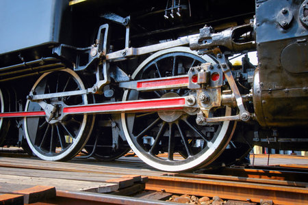 A close-up view of the drive wheels and connecting rods of a vintage steam locomotive at the...