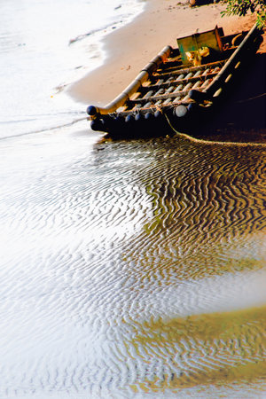 A bamboo raft rests on a sandy shore with rippling water, captured at sunset on October 7, 2012, in Miaoli County, Taiwan.の写真素材