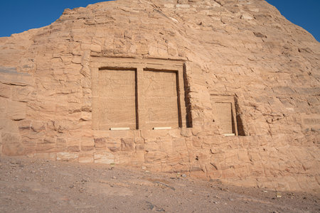 This image captures detailed ancient rock carvings found along the path to the Abu Simbel Temples in Aswan, Egypt. The carvings depict historical scenes and hieroglyphics.の写真素材