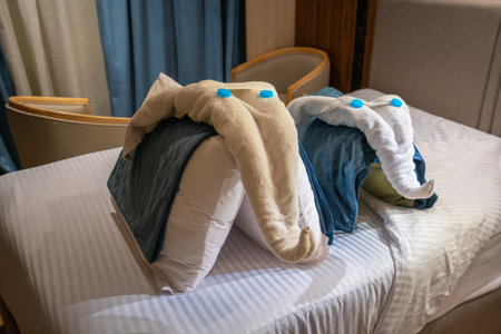 Two charming towel elephants, artfully arranged from pillows and towels, adorn a bed on a Nile River cruise in Aswan, Egypt. A delightful hospitality detail for guests.の写真素材