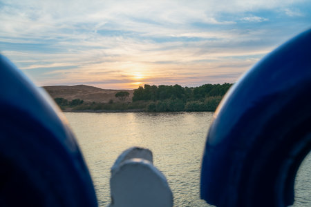 Stunning sunset view from a river cruise at Esna Lock of The Nile, Egypt, featuring serene waters and distant hills under a colorful sky.の写真素材