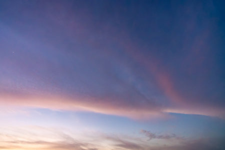 A breathtaking sunset sky over the Nile River near Esna Lock, Egypt, ablaze with vibrant pink, purple, and orange hues. The expansive sky creates a stunning backdrop for the tranquil waters at dusk.の写真素材