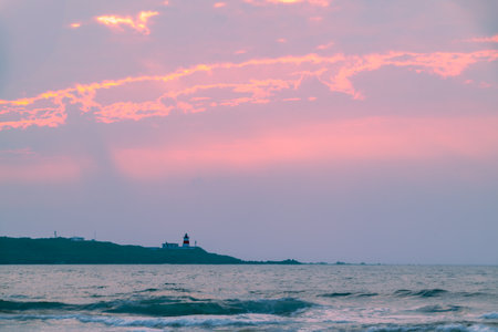 A breathtaking pink and purple sunset sky over the Fuguijiao Lighthouse and the Shimen coastline in New Taipei City, Taiwan, creating a serene and magical atmosphere.の写真素材