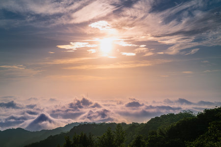Beautiful sunrise over misty mountains in Shilin New Taipei Taiwan, with a subtle Taipei City silhouette visible through the rolling clouds.の写真素材