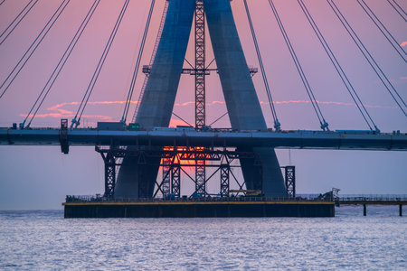 The setting sun peeks through the intricate structure of the Danjiang Bridge under construction in...