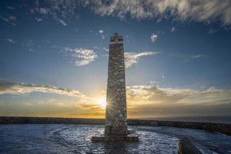 A scenic monument atop a cliff overlooking the Atlantic, with a wooden fence and vast ocean view....
