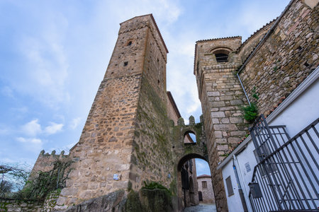 View of an ancient stone arched passageway connecting two prominent towers in the historic town of Trujillo Spain.の写真素材