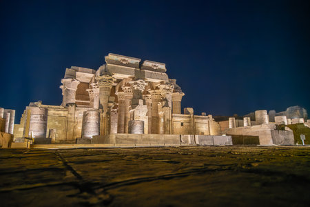 The magnificent Temple of Kom Ombo is illuminated at night against a dark sky, highlighting its ancient columns and powerful structure.の写真素材