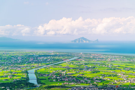 Dusk panorama from Dongshan, Taiwan, featuring Lanyang Plain, Guishan Island, distant sea, and cloud-dotted blue sky.の写真素材