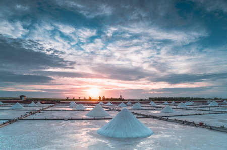 Qigu, Tainan City, Taiwan - May 18, 2025: Sunset light filters through clouds above salt fields. The shifting sky adds a dynamic, tranquil mood.の写真素材