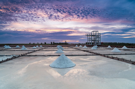 Qigu, Tainan City, Taiwan - May 18, 2025: Sunset light filters through clouds above salt fields. The shifting sky adds a dynamic, tranquil mood.の写真素材