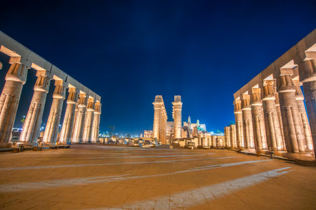 Long exposure shot of tourists viewing the illuminated pylon and courtyard of the ancient Temple of Luxor. The temple honors the Theban Triad: Amun, Mut, and Khonsu. Luxor, Egypt.の写真素材
