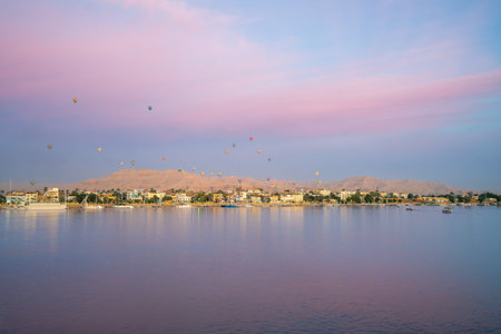 Colorful hot air balloons rise above Luxor's West Bank at dawn. Viewed from a Nile cruise, the scene...